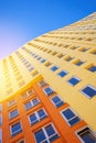 Modern European multi-storey building with many glass windows standing against background of blue sky and sun Royalty Free Stock Photo