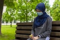 Modern european muslim woman wearing surgical face mask praying digital tespih in the park Royalty Free Stock Photo