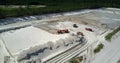 Excavator digs sand hill to load tipper at pit aerial view