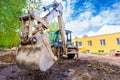 The modern excavator performs excavation work on the construction site. Front view of a digger bucket of digging ground Royalty Free Stock Photo