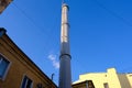 Modern exhaust pipe in an old residential area with low-rise buildings against a clean blue sky. Light gray color. Stairs. Against