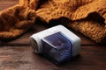 Modern fabric shaver with fuzz and orange knitted sweater on wooden table, closeup Royalty Free Stock Photo