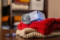 Modern fabric shaver and knitted clothes on wooden table indoors, closeup Royalty Free Stock Photo