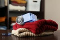 Modern fabric shaver and knitted clothes on wooden table indoors, closeup Royalty Free Stock Photo