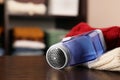 Modern fabric shaver and knitted clothes on wooden table indoors, closeup. Space for text Royalty Free Stock Photo