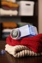 Modern fabric shaver and knitted clothes on wooden table indoors, closeup. Space for text Royalty Free Stock Photo