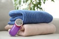 Modern fabric shaver and woolen sweaters on sofa indoors, closeup