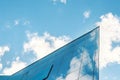 modern facade of glass and steel with reflections. Abstract or graphic photo of the sky with clouds seeming to continue into a Royalty Free Stock Photo