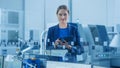 Modern Factory Office: Portrait of Young and Confident Female Industrial Engineer Standing and Hol