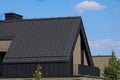 A modern family home with a trendy design. Gray roof, sand walls against the blue sky.