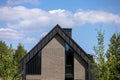 A modern family home with a trendy design. Gray roof, sand walls against the blue sky.