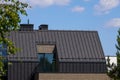 A modern family home with a trendy design. Gray roof, sand walls against the blue sky.