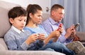 Modern family sitting with smartphones in home interior Royalty Free Stock Photo