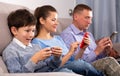 Modern family sitting with smartphones in home interior Royalty Free Stock Photo