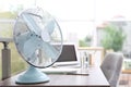 Modern fan on wooden table in office, space for text. Summer heat Royalty Free Stock Photo