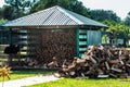 Modern farm with a beautiful lawn and a firewood shed. the logs lie neatly under the canopy. near a pile of ribbed wood Royalty Free Stock Photo