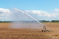 Modern farm water sprinkler irrigation system watering field during dry weather