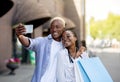 Modern fashion bloggers shopping. Smiling couple with bags hugging and making selfie for blog