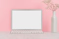 Modern fashion workplace - silver laptop with blank screen, white stationery on soft pink background.