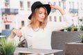 Modern fashionable young woman hipster in a luxurious black hat in a knitted sweater with sunglasses posing at a gray table Royalty Free Stock Photo