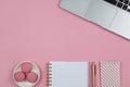 Modern female working space, top view. Laptop, notebooks, pen in rose gold color, macarons on pink background, copy space, flat