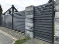 Modern fence of vertical grey metal bars and ranite gray tiles