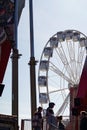 modern ferris wheel with closed cabins at carnival with blue sky no clouds in the background illuminated wide angle close up shot