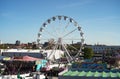 modern ferris wheel with closed cabins at carnival with blue sky no clouds in the background illuminated wide angle close up shot