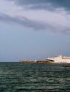 Modern ferry docking at pier on cloudy day, surrounded by calm sea and featuring small lighthouse in background Royalty Free Stock Photo