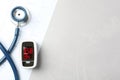 Fingertip pulse oximeter, stethoscope and cardiogram on grey stone table, flat lay. Space for text Royalty Free Stock Photo