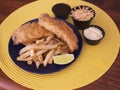 Modern fish and chips plate with coleslaw, sauces and lime