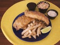 Modern fish and chips plate with coleslaw, sauces and lime