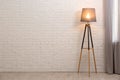 Modern floor lamp against brick wall indoors