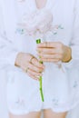 Modern floral aesthetic, green trendy tone. Stylish girl in white floral shirt gently holding peony flower in hands with jewelry