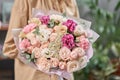 Modern floral shop. Finished work of the florist. Cute bouquet of mixed flowers in womans hands. Delivery fresh cut