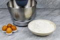 Modern food processor, eggs and plate with flour on a kitchen table