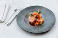 Modern French cuisine: Roasted Lamb neck & rack served with carrot, yellow curry and lamb sauce. Served in black stone plate. Royalty Free Stock Photo