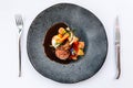 Modern French cuisine: Roasted Lamb neck & rack served with carrot, yellow curry and lamb sauce. Served in black stone plate. Royalty Free Stock Photo