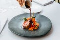 Modern French cuisine: Roasted Lamb neck & rack served with carrot, yellow curry and lamb sauce. Served in black stone plate. Royalty Free Stock Photo