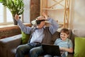 Portrait of happy senior man and little boy, grandfather and grandson using VR glasses sitting on sofa at home and Royalty Free Stock Photo