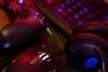 Modern gamepad and gaming mouse lies with keyboard and headphones on table in dark playroom scene. Background composition for