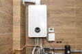 A modern gas boiler for natural gas, installed in a boiler room lined with ceramic tiles.