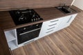 A modern gas cooker with ceramic hob, electric oven and a dark brown wooden kitchen with wash-basin ready for cooking a meal Royalty Free Stock Photo