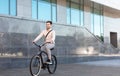 Modern generation and healthy lifestyle. Young businessman going to work by bike