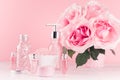 Modern gentle girlish bathroom decor - cosmetics for bath, spa, bouquet of roses, bath accessories on soft white wooden table.