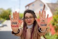 Modern girl with long dreadlocks and eyeglasses in nude color trench is showing hands with written slogan `Our future in Royalty Free Stock Photo