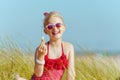 Modern girl in red swimwear holding lipstick with spf on beach