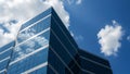Modern glass building reflecting blue sky and white clouds architecture Royalty Free Stock Photo
