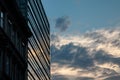 Modern glass building used as an office place in the sunset with an older building just next to it.