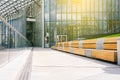 This is a modern glass building. Wooden bench and concrete walkway. Office building for the work of company employees